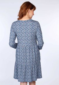 Blaues, floral gemustertes knielanges Kleid mit langen Ärmeln, rundem Ausschnitt und geraffter Taille, die den gestuften Rock betont.