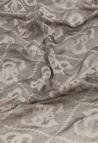 Tissu gris à motifs avec une texture fluide présentant un design floral subtil. Le tissage est complexe, combinant des tons clairs et foncés.