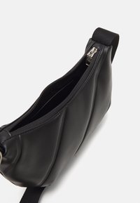 Černá kabelka na rameno z umělé kůže s prošívanou texturou, horní zipové uzavření a odolný látkový popruh pro snadné nošení.