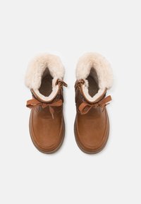 Braune Leder-Stiefeletten mit weichem cremefarbenem Kunstfell-Futter, dekorativem Bogen und seitlichem Reißverschluss, mit runder Zehenpartie und strukturiertem Sohlen.