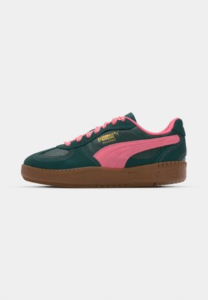 Grønn semsket sneakers med rosa detaljer, gullmerke, og en teksturert brun gummisåle. Snøring; klassisk sporty design.