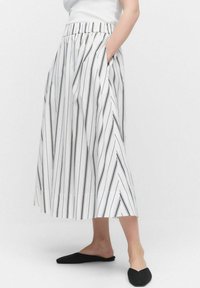 Jupe midi blanche avec des rayures verticales noires, dotée d'une taille élastique et de poches latérales. Texture lisse, forme évasée.