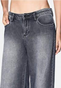 Losse grijze spijkerbroek van denim met een vervaagde was, voorzakken, een knoopsluiting en contrasterende stikseldetails.