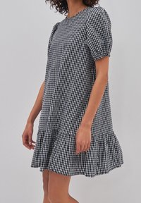 Svartvit rutigt kortärmad klänning med volangkant. Tillverkad av lättviktig tyg, har en loose fit och puffärmar.