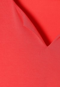 Haut rouge à col en V fabriqué en tissu lisse et extensible avec une coupe ajustée. Doté de coutures nettes et d'une texture légèrement brillante.