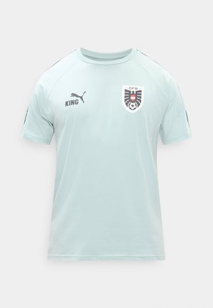 Hele sinine lühikese varrukaga spordisärk Puma logoga, rinnal tekst "KING" ja Austria Jalgpalliliidu embleem.