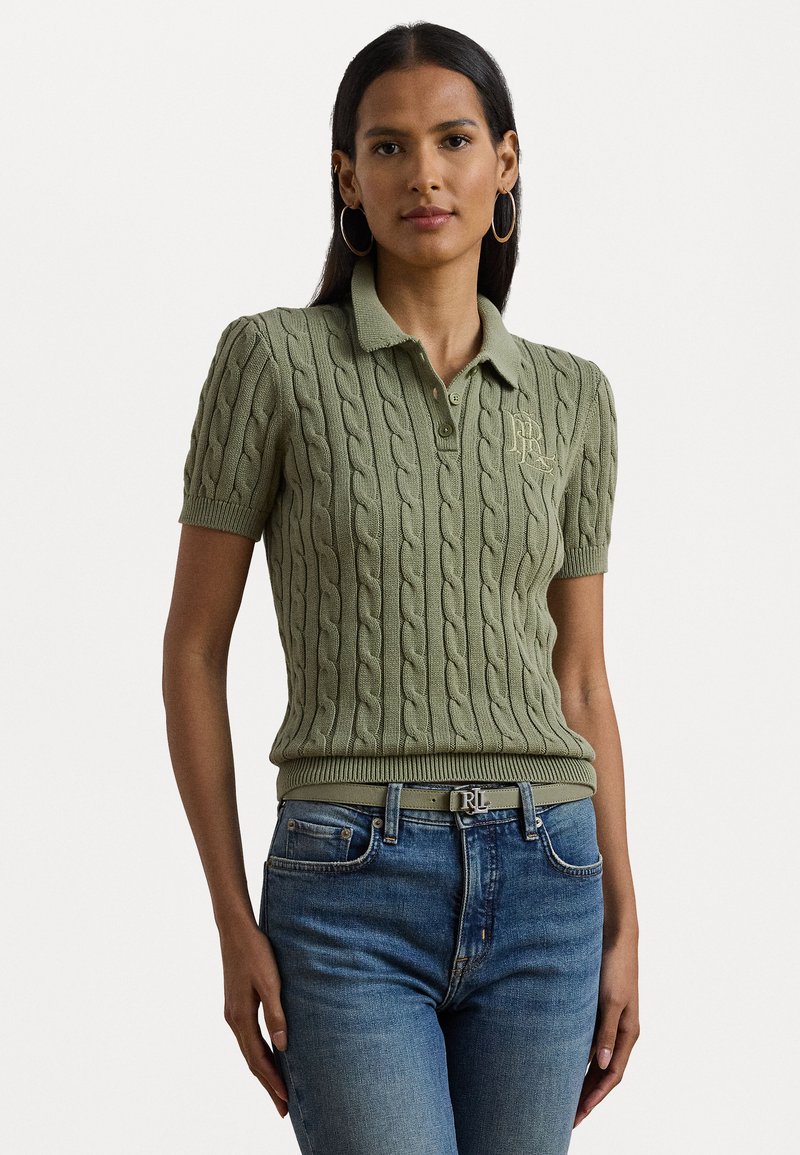 Polo-shirt en tricot câble vert clair avec des manches courtes, un col et un logo brodé. Assorti avec un jean bleu et une ceinture assortie.