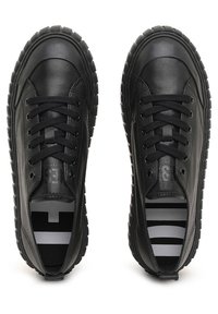 Zapatillas de cuero negro con punteras redondas, suelas de goma texturizadas y diseño con cordones. El forro interior presenta rayas en gris y negro.