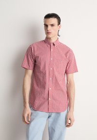 Chemise à manches courtes à carreaux rouges et blancs avec un col boutonné, ornée d'un petit logo sur la poche poitrine, fabriquée en tissu léger.