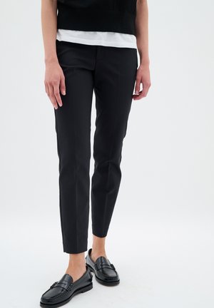 Sorte skræddersyede bukser med en tætsiddende pasform, der har en glat, vævet tekstur og enkle linjer. Matcher med sorte loafers og en hvid top.