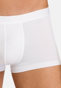White men's boxer briefs made from a smooth, stretchy material. Elastic waistband features subtle brand logo. Fitted design, knee-length cut.