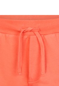 Coralowe pomarańczowe dresy z elastycznym paskiem na sznurki, miękką teksturą i marszczonym detalem przy talii.