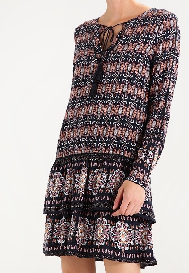Robe noire à manches longues avec des motifs floraux et géométriques complexes en rose et blanc, dotée d'un détail à nouer au col et d'une jupe à volants.