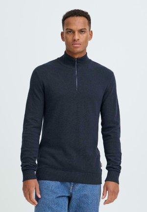 Marineblauwe trui met ritskraag in een gestructureerde breiwijze, voorzien van lange mouwen en geribde boorden en zoom. Gemaakt van een zachte, rekbare stof.