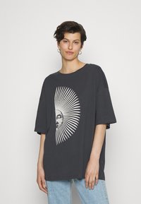 Tmavě šedé oversized tričko z bavlny s grafickým potiskem slunce a paprsků v bílé barvě, krátké rukávy a kulatý výstřih.