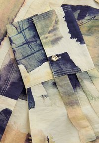 Button-up shirt featuring an abstract watercolor pattern in green, blue, and beige tones. Lightweight fabric with pleats and stitching details.