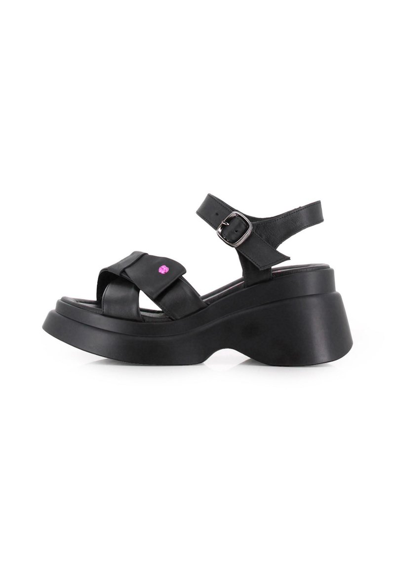 Sandalias de plataforma negras de cuero, con tiras entrecruzadas, una hebilla ajustable en el tobillo y un pequeño acento rosa en la parte delantera.