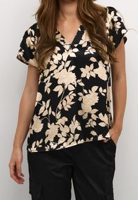 Mustikka kukkakuviollinen pusero, jossa on kermaisen väriset ruusukuviot. V-aukko ja lyhyet hihat. Pehmeä kangas, jossa on rento istuvuus.