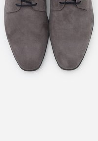 Gray suede dress shoes with a pointed toe design, featuring flat laces and subtle stitching details. Smooth texture and sleek silhouette.