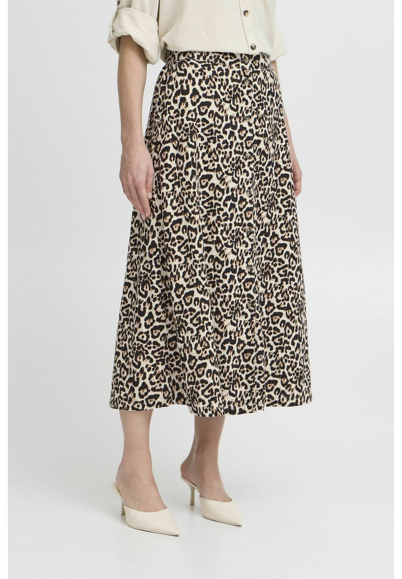 Plettet midi-skjørt i leopardprint, i beige og sort farveskema, blød stofkvalitet, parret med spidse hvide heels.