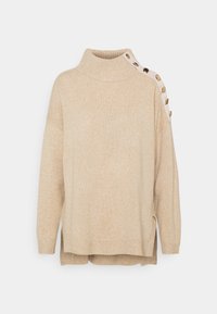 Beżowy sweter z wysokim kołnierzem, miękką dzianiną i bocznymi guzikami. Posiada luźny krój oraz prążkowane mankiety i dół.