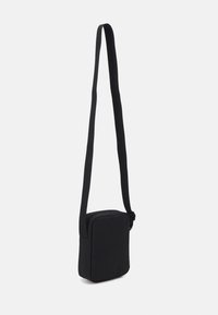 Černá obdélníková crossbody taška s hladkou texturou, nastavitelným popruhem a zipovým uzávěrem. Minimalistický design, vhodná pro každodenní používání.