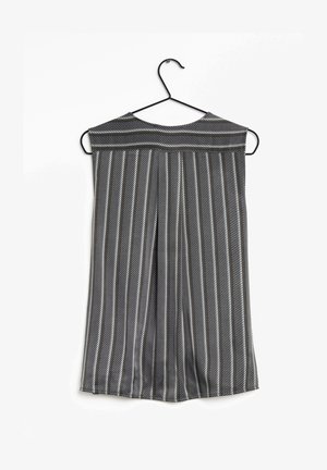 Top sin mangas con rayas blancas y negras, con escote redondeado y diseño plisado, colgado en una percha de alambre negra sobre un fondo blanco.