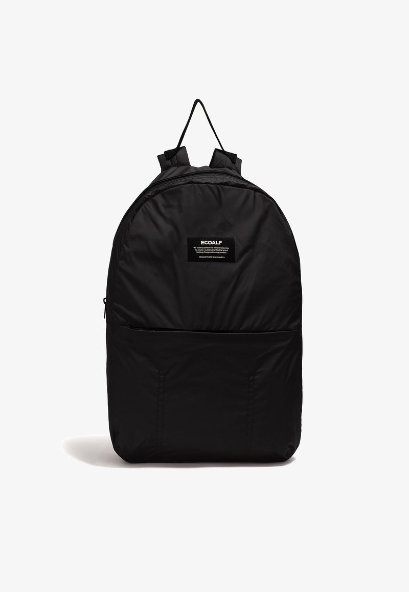 Sac à dos noir simple avec une poche zippée à l'avant, des bretelles rembourrées, une poignée supérieure et une petite étiquette de marque rectangulaire au centre supérieur.