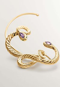 Pulsera en forma de serpiente dorada con escamas intrincadas. Presenta dos piedras preciosas moradas y acentos verdes. Acabado suave, diseño audaz y curvatura única.