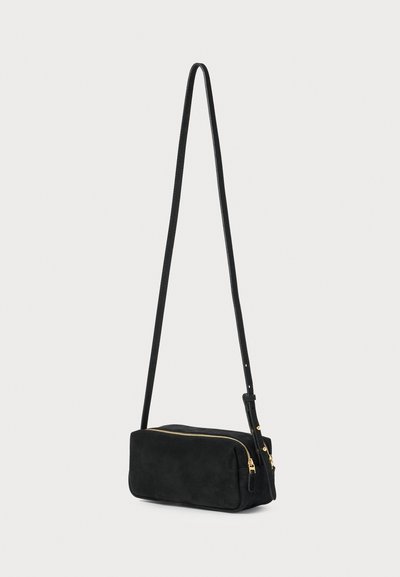 Borsa a tracolla in suede nera con forma rettangolare, zip in metallo dorato e una lunga tracolla regolabile. Texture liscia, hardware minimale.