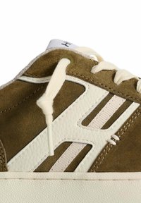 Sneaker in suede marrone con dettagli in pelle bianca, lacci tondi e suola in gomma testurizzata. Presenta un logo prominente sul lato.