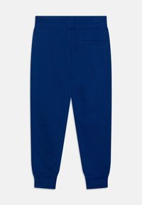 Marinblå joggerbyxor med elastiskt midjeband, en bakficka med slits och ribbade fållar vid anklarna.