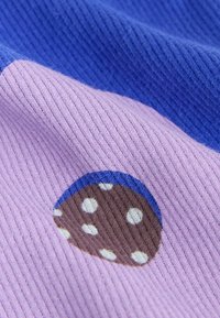 Tessuto a coste viola e blu con una macchia marrone testurizzata decorata con pois bianchi. Il materiale sembra morbido e intrecciato.