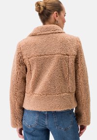 Braune, kuschelige Teddyjacke mit Kragen, strukturiertem Stoff und cropped Design. Verfügt über gestickte Details und seitliche Taschen.
