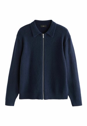 Suéter azul marino con cremallera en el frente, cuello estructurado, puños y dobladillo acanalados. Fabricado con una tela suave y texturizada.