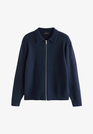 Suéter azul marino con cremallera en el frente, cuello estructurado, puños y dobladillo acanalados. Fabricado con una tela suave y texturizada.