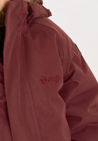 Bordeaux jack gemaakt van textielstof, met een ritssluiting en geborduurd "ZIGZAG" logo op de linker borst.