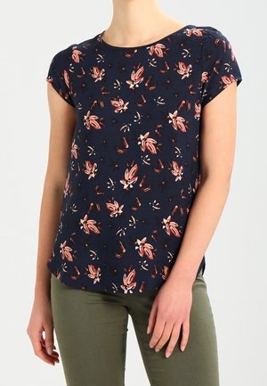 Marineblauwe bloe blouse met korte mouwen, voorzien van roze en witte bloemenpatronen. Lichtgewicht stof met een relaxte pasvorm en een ronde hals.