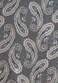 Marineblaue Stoff mit einem Paisleymuster in Gold und Weiß, das aufwändige florale Details und einen strukturierten Hintergrund aufweist.