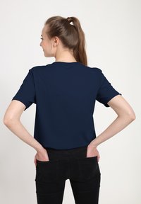 T-shirt bleu marine à manches courtes fabriqué en tissu doux, présentant un col rond et une coupe décontractée, vu de dos.