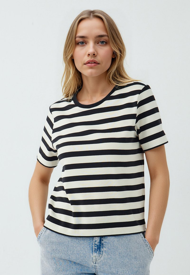 T-shirt a righe con strisce orizzontali nere e off-white, maniche corte, colletto a girocollo e vestibilità comoda. Abbinato a jeans in denim chiaro.