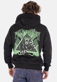 Felpa nera con cappuccio caratterizzata da una grande grafica verde di un leone ruggente all'interno di un design triangolare con foglie di palma e testo stilizzato.