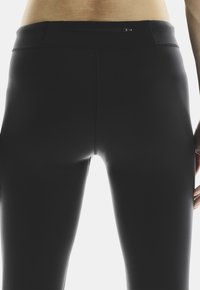 Svarta atletiska leggings har ett slätt, elastiskt tyg, hög midja och en dold dragkedjeficka på baksidan för förvaring.