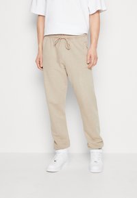 Beiga bomullssweatpants med elastisk midjeband, dragsko, sidofickor och broderad logodetalj på vänster ben.