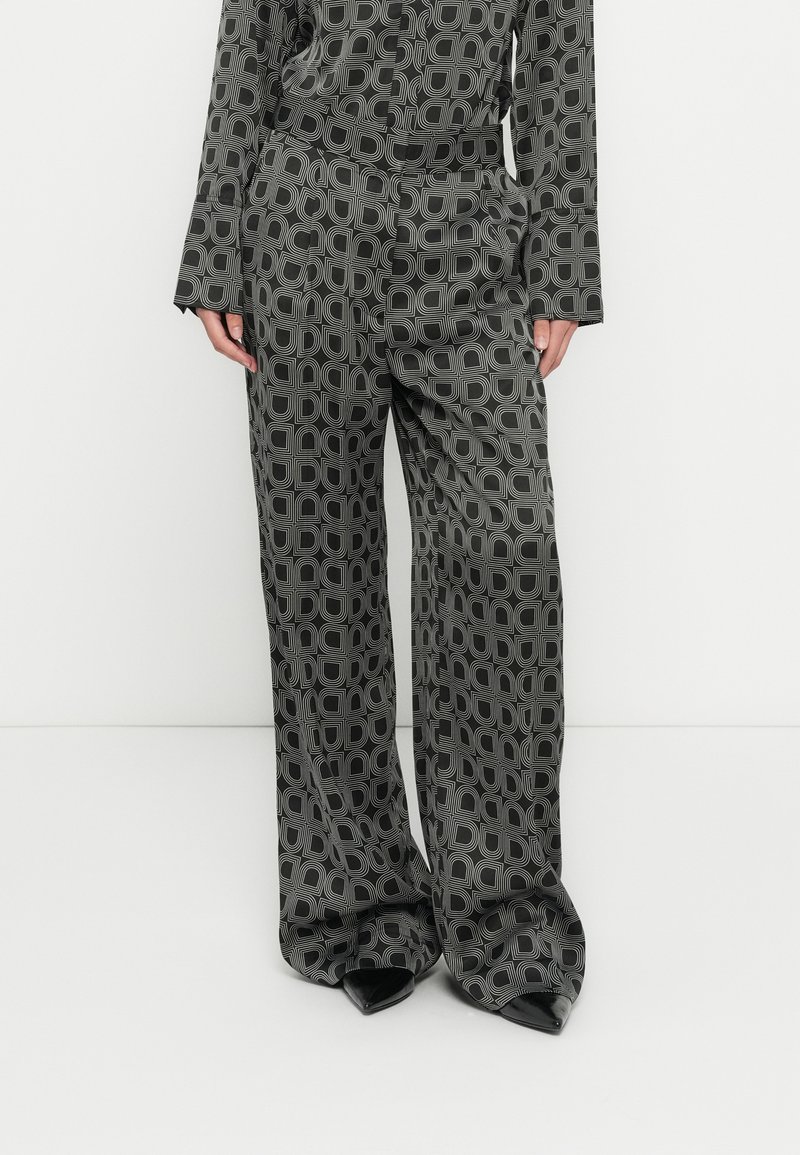 Čierne široké nohavice s potlačou, ktoré majú grafický dizajn prekrytých tvarov, s hladkou textúrou a vysokým pásom.
