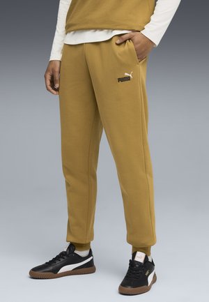 Puma sweatpants i senapsgul med elastiska muddar, har fickor och en vit logotyp. Matchade med svarta sneakers med bruna sulor.