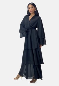 Zwarte maxi-jurk met meerdere lagen, brede mouwen, een getailleerde taille en een vloeiende silhouet. Gemaakt van lichtgewicht stof met een gladde textuur.