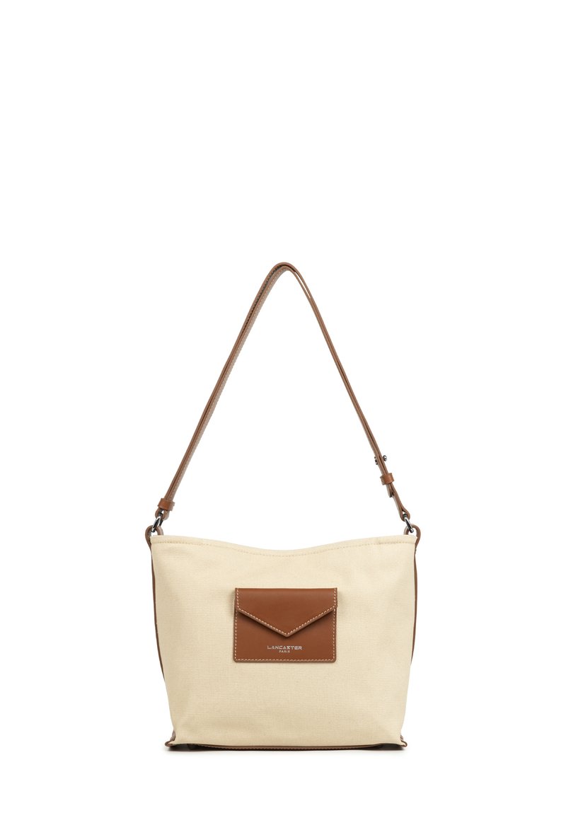 Borsa a spalla in tela beige con una tasca in pelle marrone e tracolla. Texture morbida, forma curvata e dettagli di cucitura presenti.