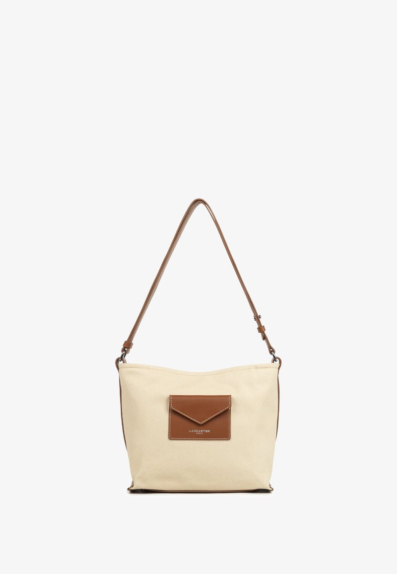 Borsa a spalla in tela beige con una tasca in pelle marrone e tracolla. Texture morbida, forma curvata e dettagli di cucitura presenti.