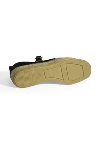 Schwarzer Schuh mit strukturiertem Obermaterial, featuring einem Schnallen-Detail und einer gelben Gummisohle mit geriffeltem Muster für besseren Halt.